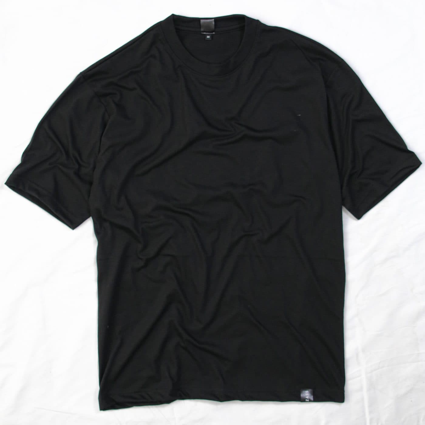 เสื้อยืดโอเวอร์ไซซ์สีดำเปล่า วางแบน ติดป้ายทอที่ชายเสื้อ