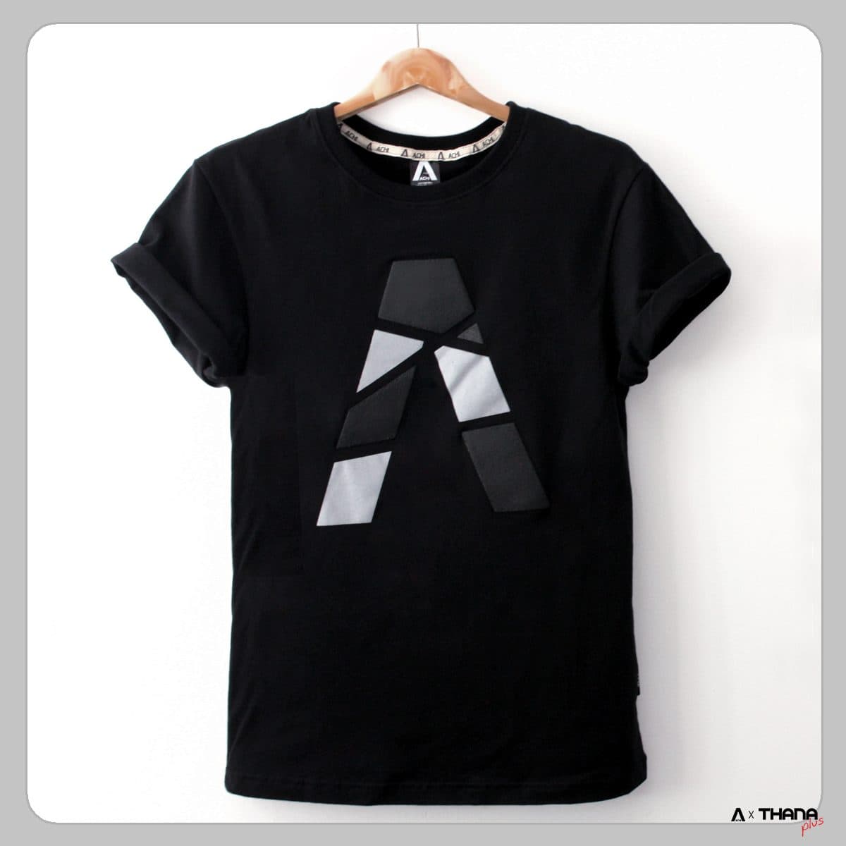 เสื้อยืดสีดำแขวนบนไม้แขวน สกรีนโลโก้ตัว A สีขาวและเทา