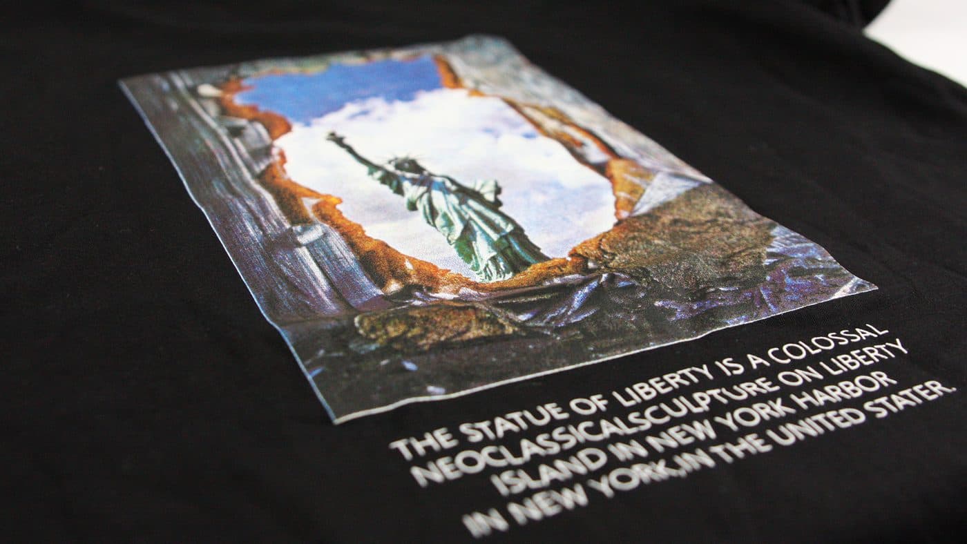 เสื้อยืดสีดำสกรีนภาพสีรูปเทพีเสรีภาพและตัวอักษรสีขาว
