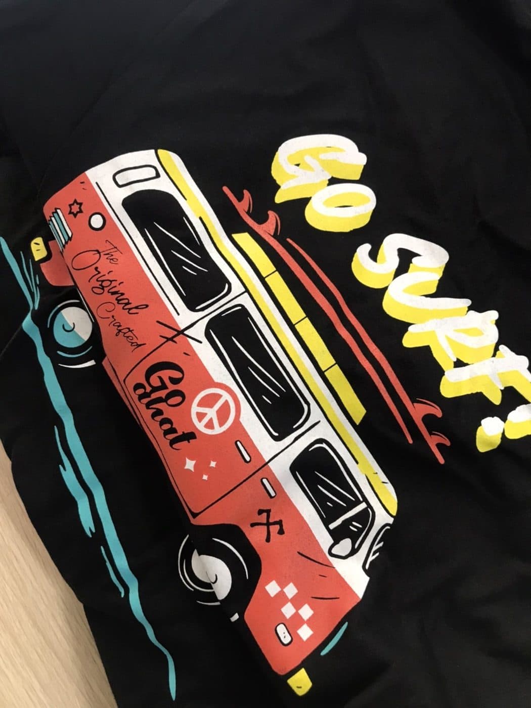 เสื้อยืดสีดำสกรีนลายรถตู้สีแดงขาวและตัวอักษร GO SURF