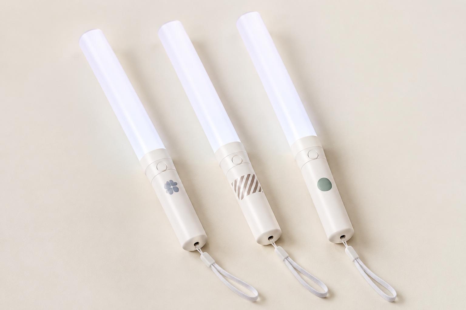 แท่งไฟ LED 3 แท่งสกรีนลายเรียบๆ คนละตำแหน่งบนด้าม วางบนพื้นสีครีม